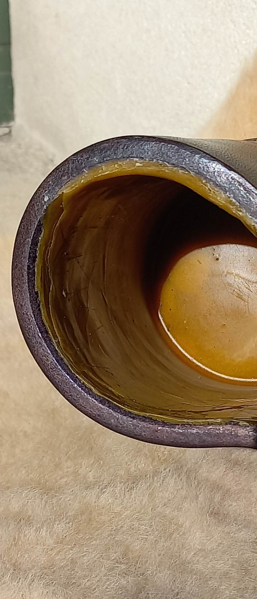 The interior of a Replica 17th Century Blackjack made from quality bullock hide from Dunedin, complete with handle, sitting atop a wool carpet.