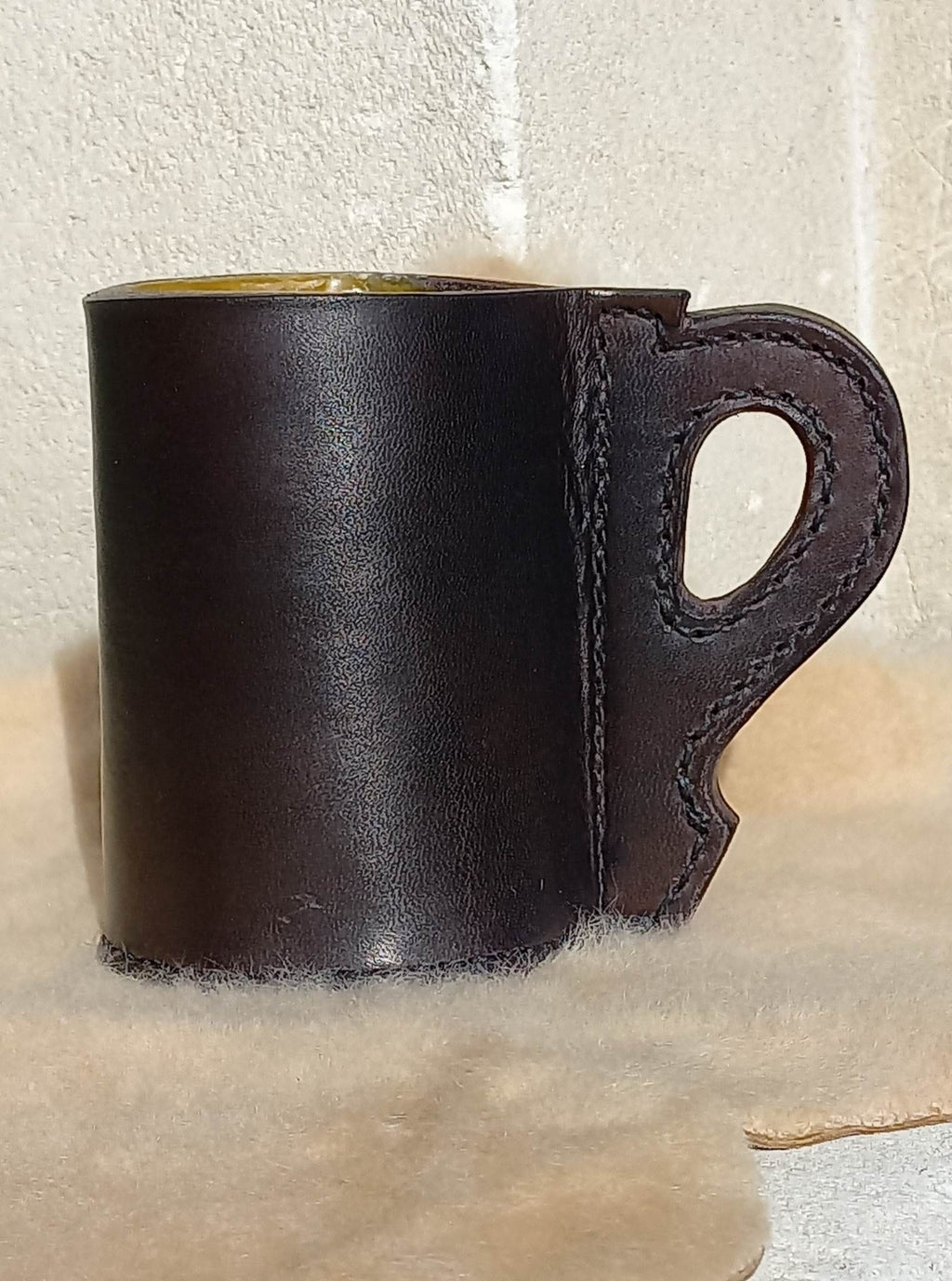 Replica 17th Century Blackjack made from quality bullock hide from Dunedin, complete with handle, sitting atop a wool carpet.