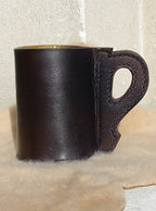 Replica 17th Century Blackjack made from quality bullock hide from Dunedin, complete with handle, sitting atop a wool carpet.