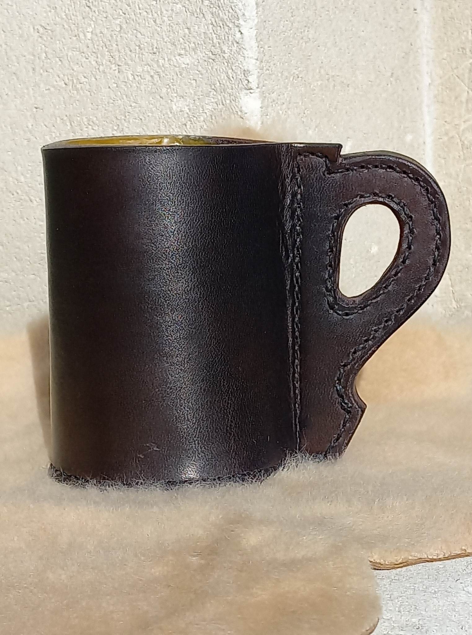 Replica 17th Century Blackjack made from quality bullock hide from Dunedin, complete with handle, sitting atop a wool carpet.