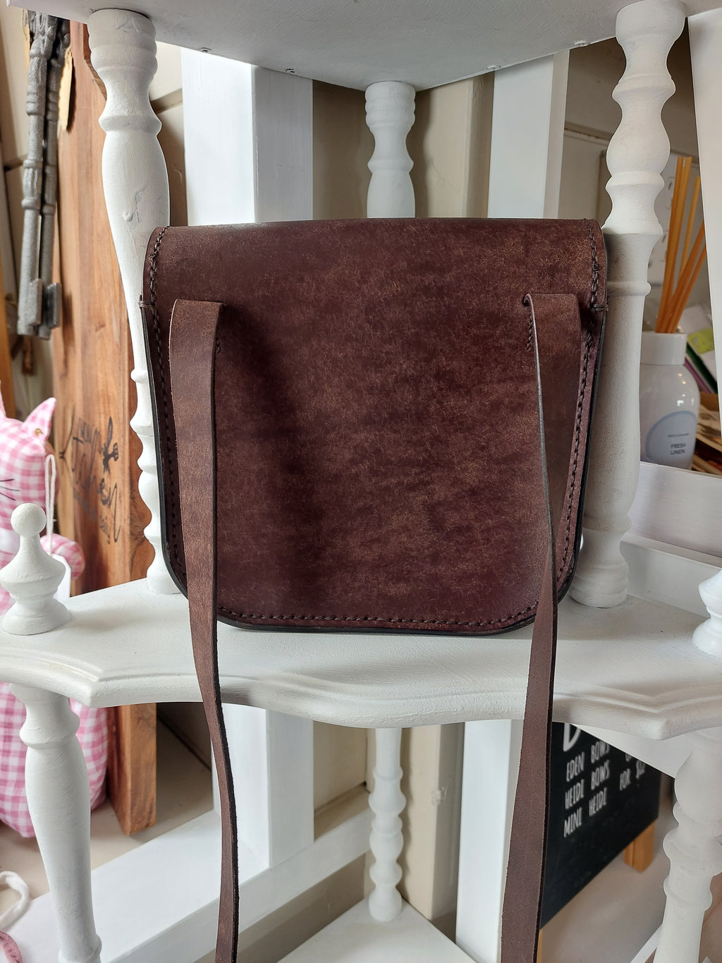 Back view of The All Day Bag with shoulder strap, hand-crafted with chocolate brown leather and brass hardware. Stamped with the Albannach Crafts logo.