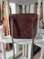 Back view of The All Day Bag with shoulder strap, hand-crafted with chocolate brown leather and brass hardware. Stamped with the Albannach Crafts logo.