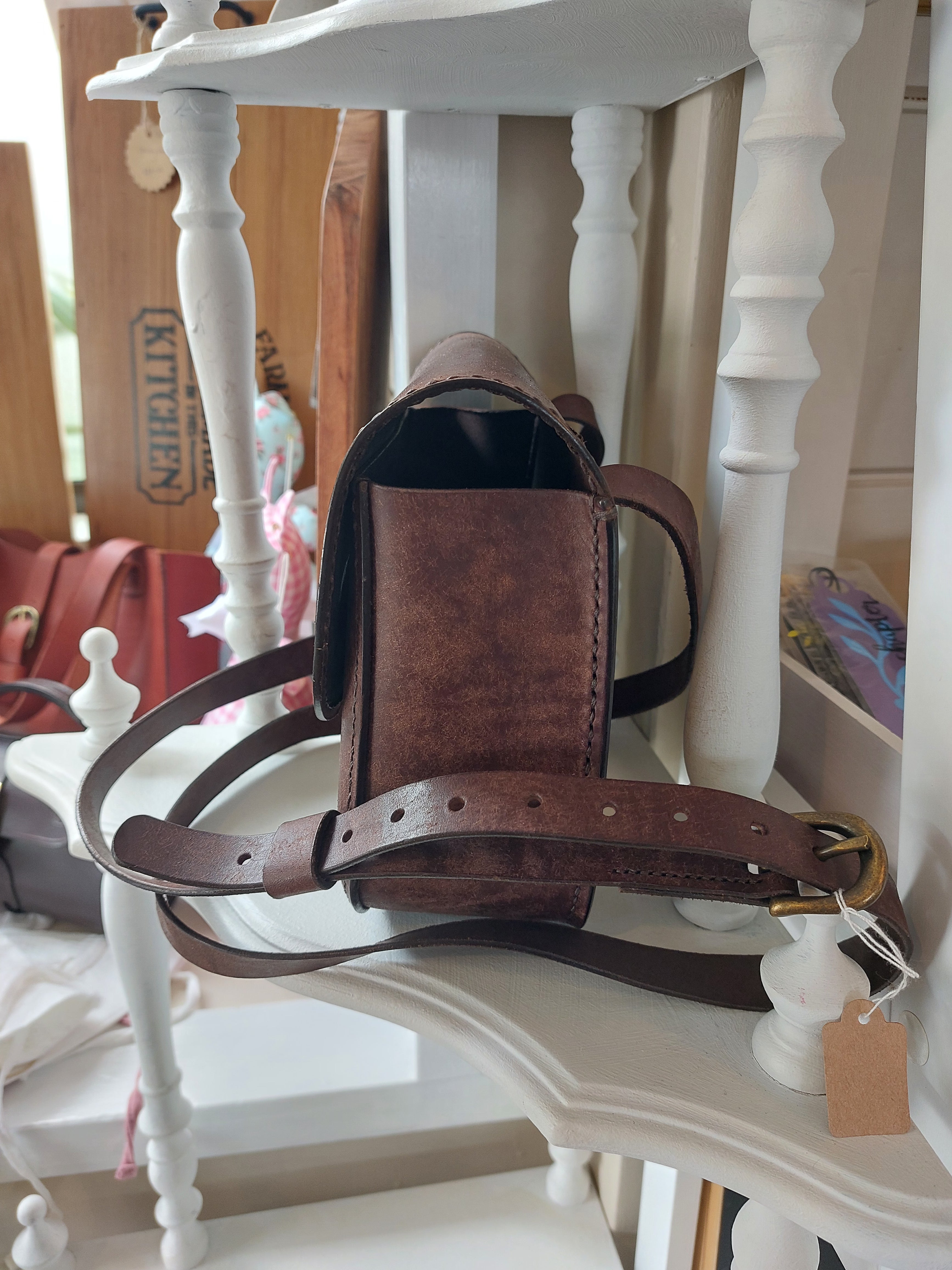 Side view of The All Day Bag with shoulder strap, hand-crafted with chocolate brown leather and brass hardware. Stamped with the Albannach Crafts logo.