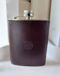 Silver alcohol flask cover case hand-made with dark brown leather and stamped with the Albannach Crafts logo.