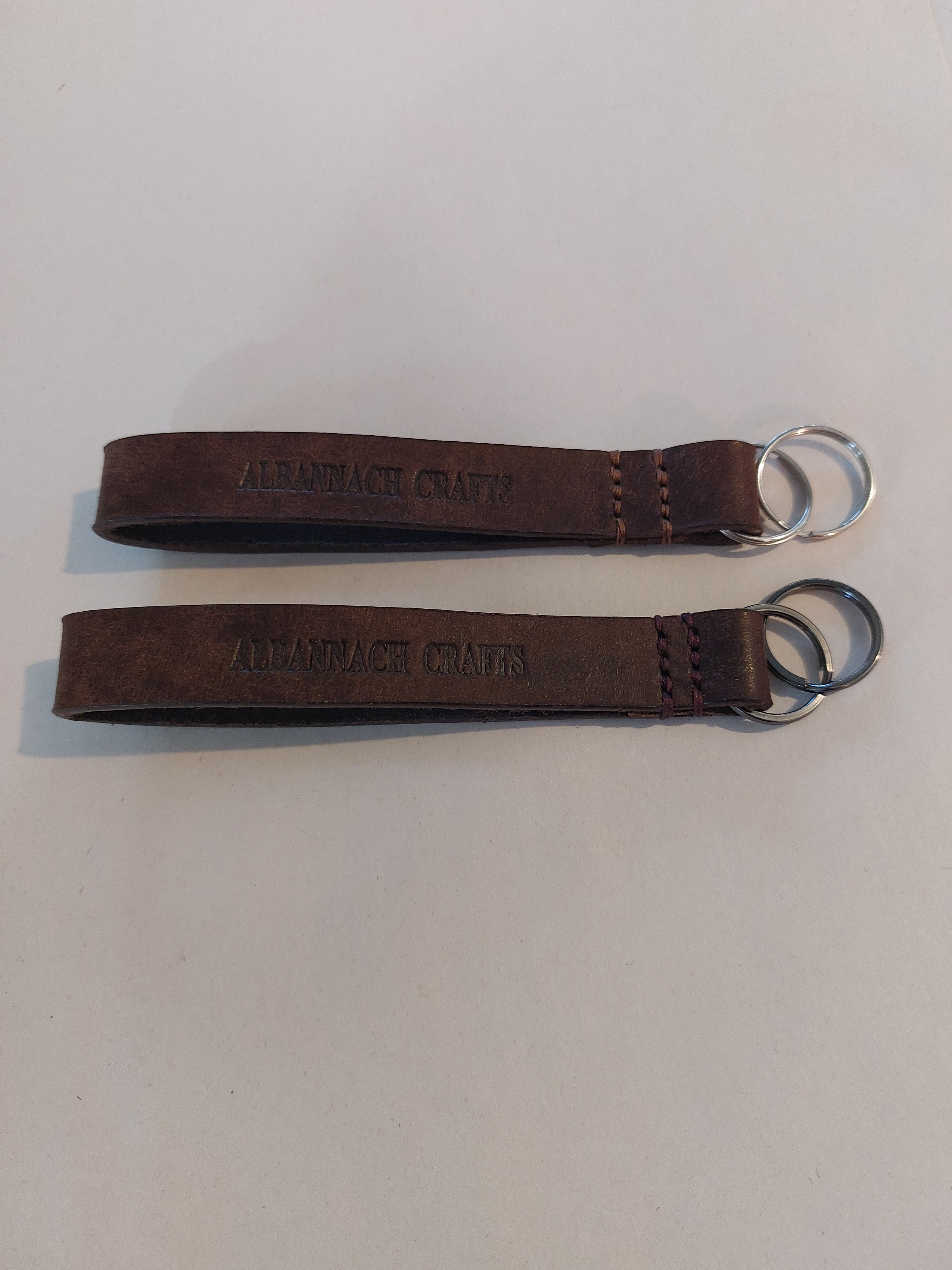 Strap Key Fob made from brown leather, stamped with the Albannach Crafts wordmark on one side.
