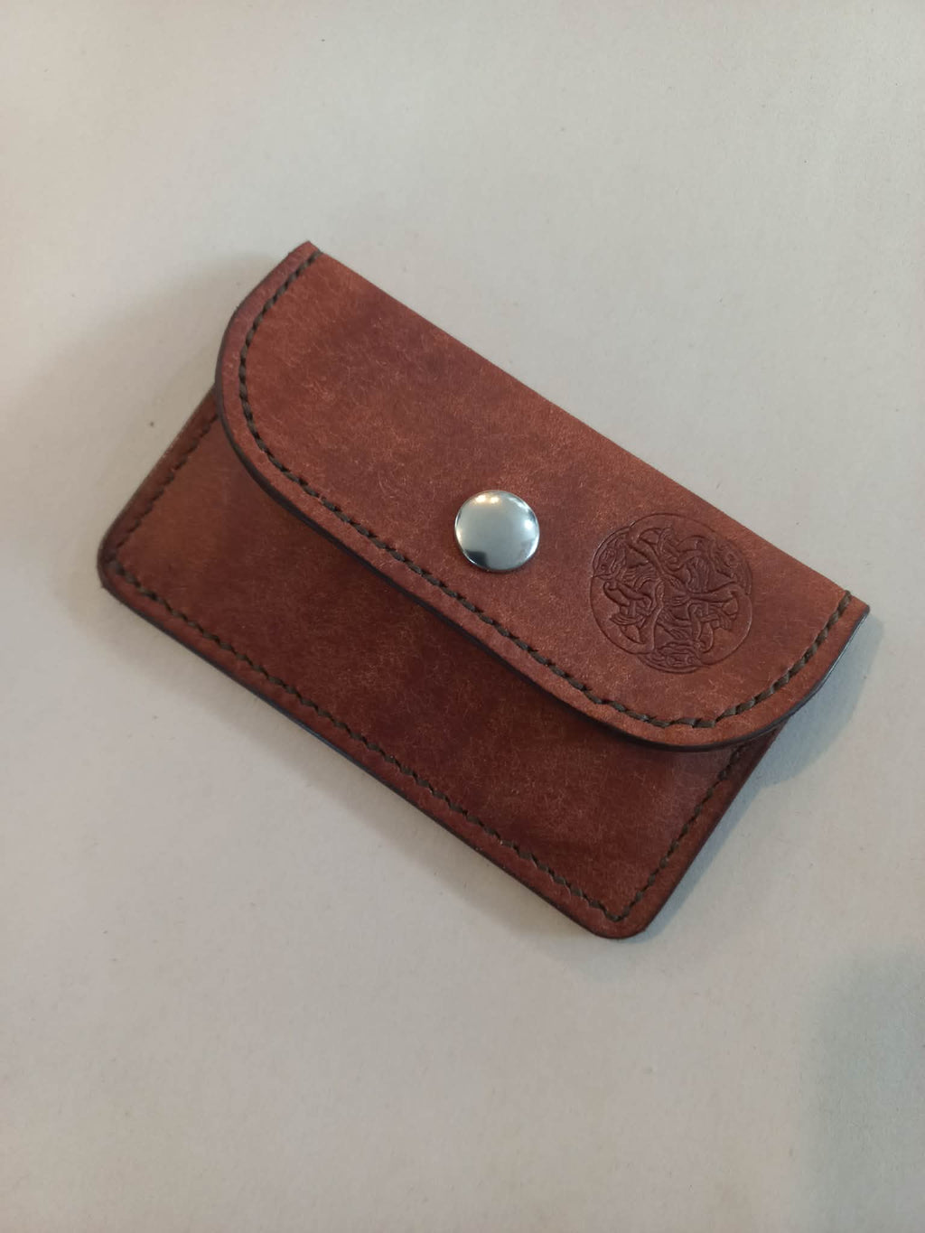 Minimalist Card & Coin Purse in Whiskey made with rich brown marble-effect leather, with the flap closed displaying the Albannach Crafts logo.