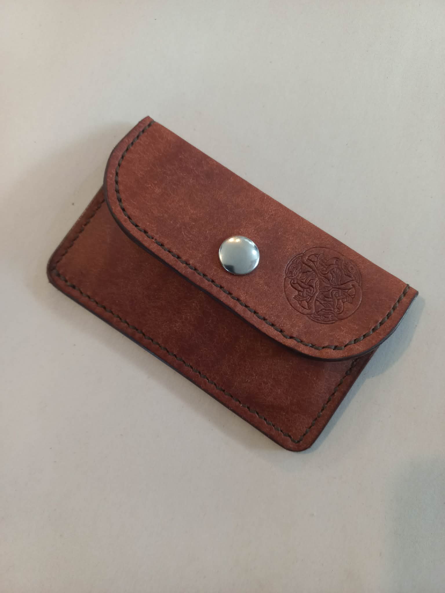 Minimalist Card & Coin Purse in Whiskey made with rich brown marble-effect leather, with the flap closed displaying the Albannach Crafts logo.