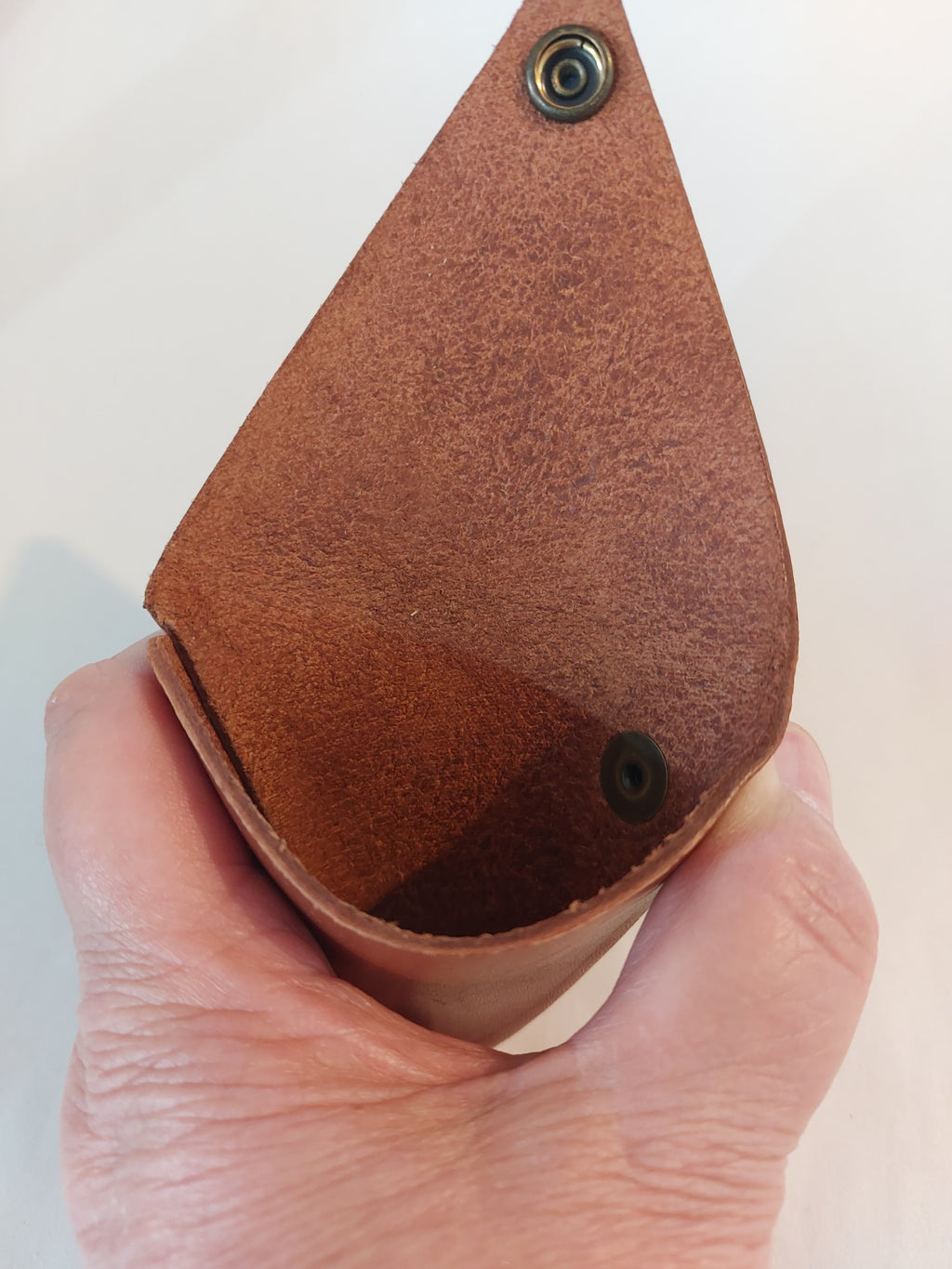 Inside of the Triangle Coin Purse made with light brown vegetable-tanned leather, with a brass closure.