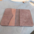 Passport Wallet made with quality brown vegetable-tanned leather, placed open and face-up on an apron.