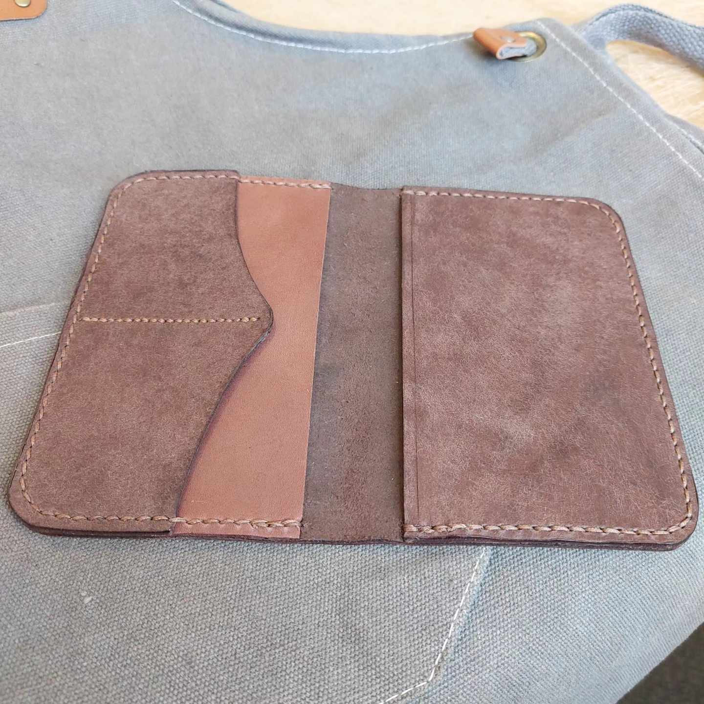 Passport Wallet made with quality brown vegetable-tanned leather, placed open and face-up on an apron.